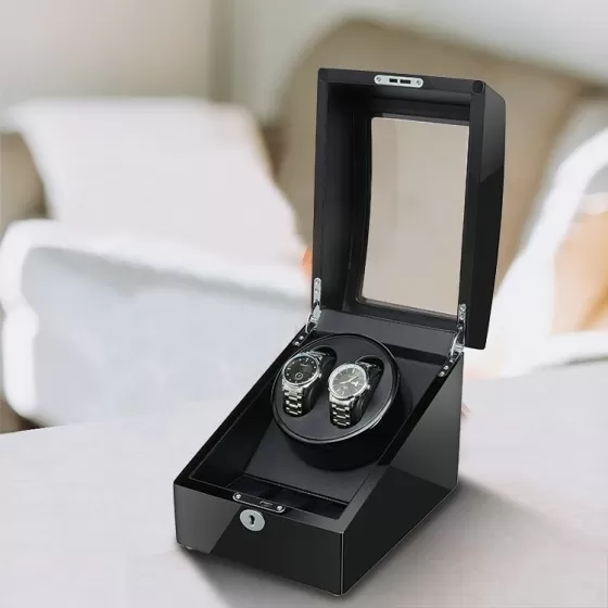 Sleek black double automatic watch winder on a bedroom dresser, silently keeping two luxury watches wound and ready to wear