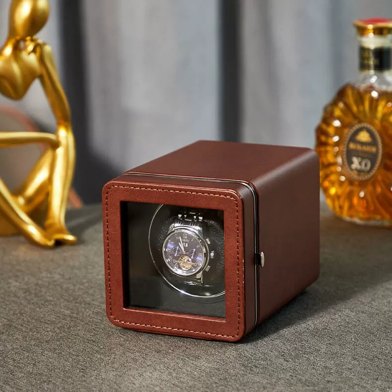 Una caja enrollable automática de cuero marrón que exhibe un reloj mecánico con esfera azul.